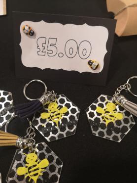 hexagonal shape acrylic with bee and honey comb image with the words beekind, keyring and tassel