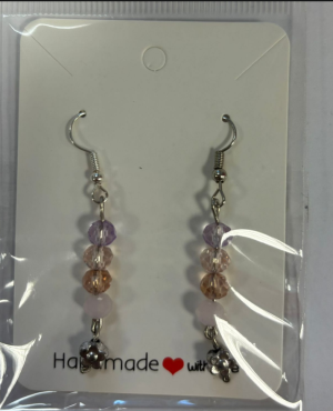 A earring with a silver hook with a purple, pink, light orange and pink layered and a silver flower at the end