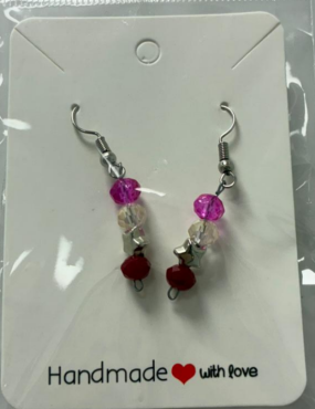 A earring with silver hooks and purple, clear beads and a silver star and a dark red bead