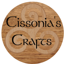 A wooden circle with a wooden triskelion and the text Cissonia's Crafts.