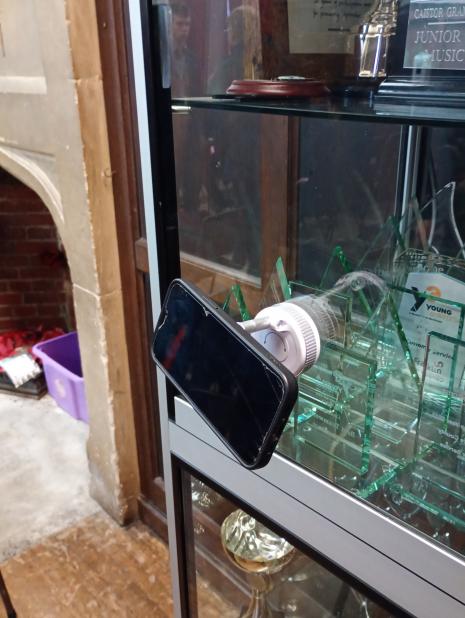 A demonstration of the product holding a phone on a glass cabinet